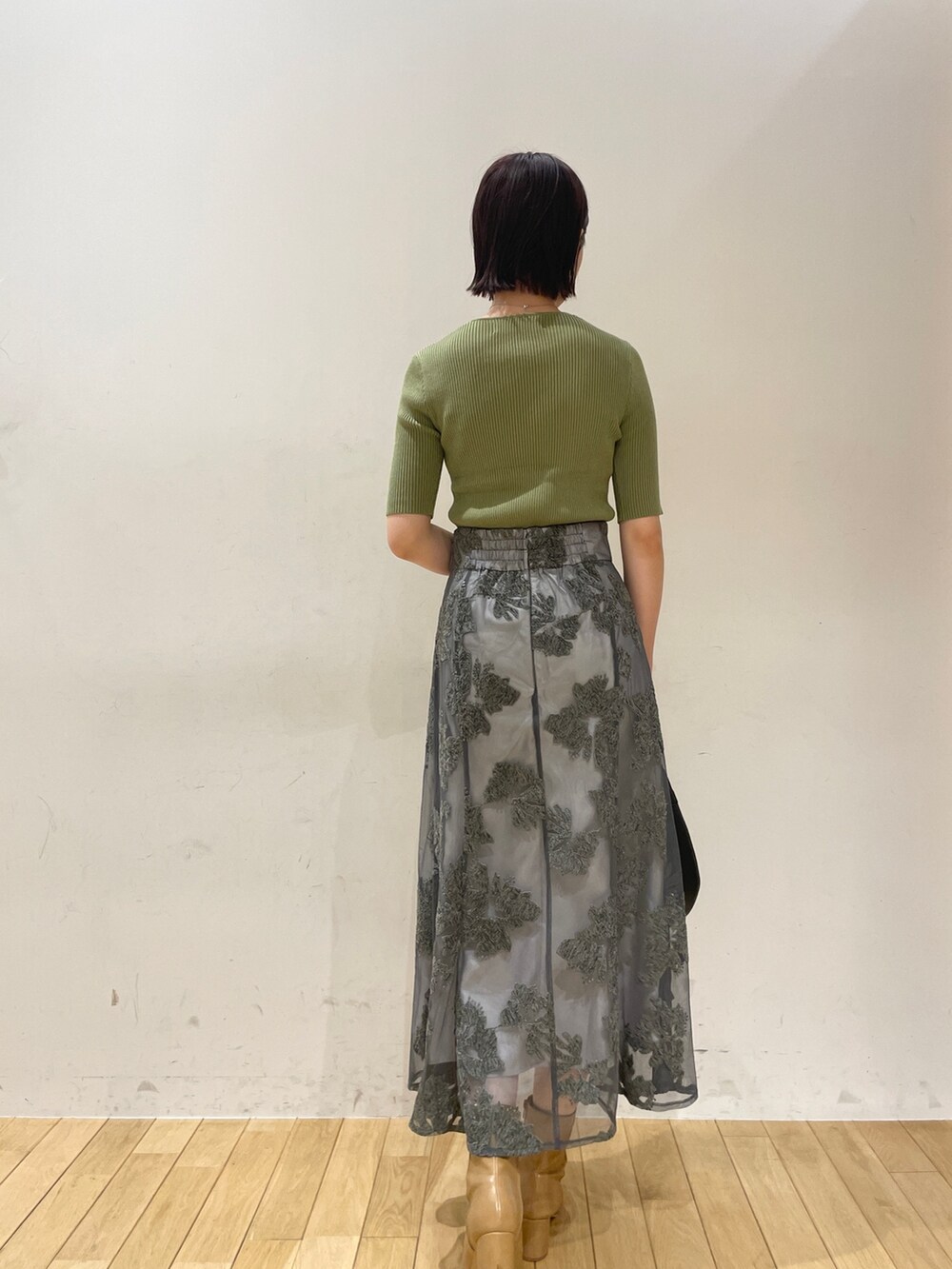 ベージュ系のブーツ、グリーン系のニット/セーター、グレー系のスカートを着用したレディースの夏コーディネートの5枚目の写真