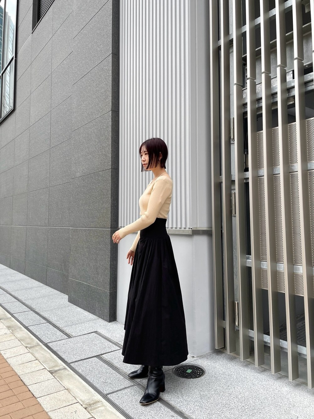 ブラック系のブーツ、ホワイト系のニット/セーター、ブラック系のスカートを着用したレディースの冬コーディネートの3枚目の写真