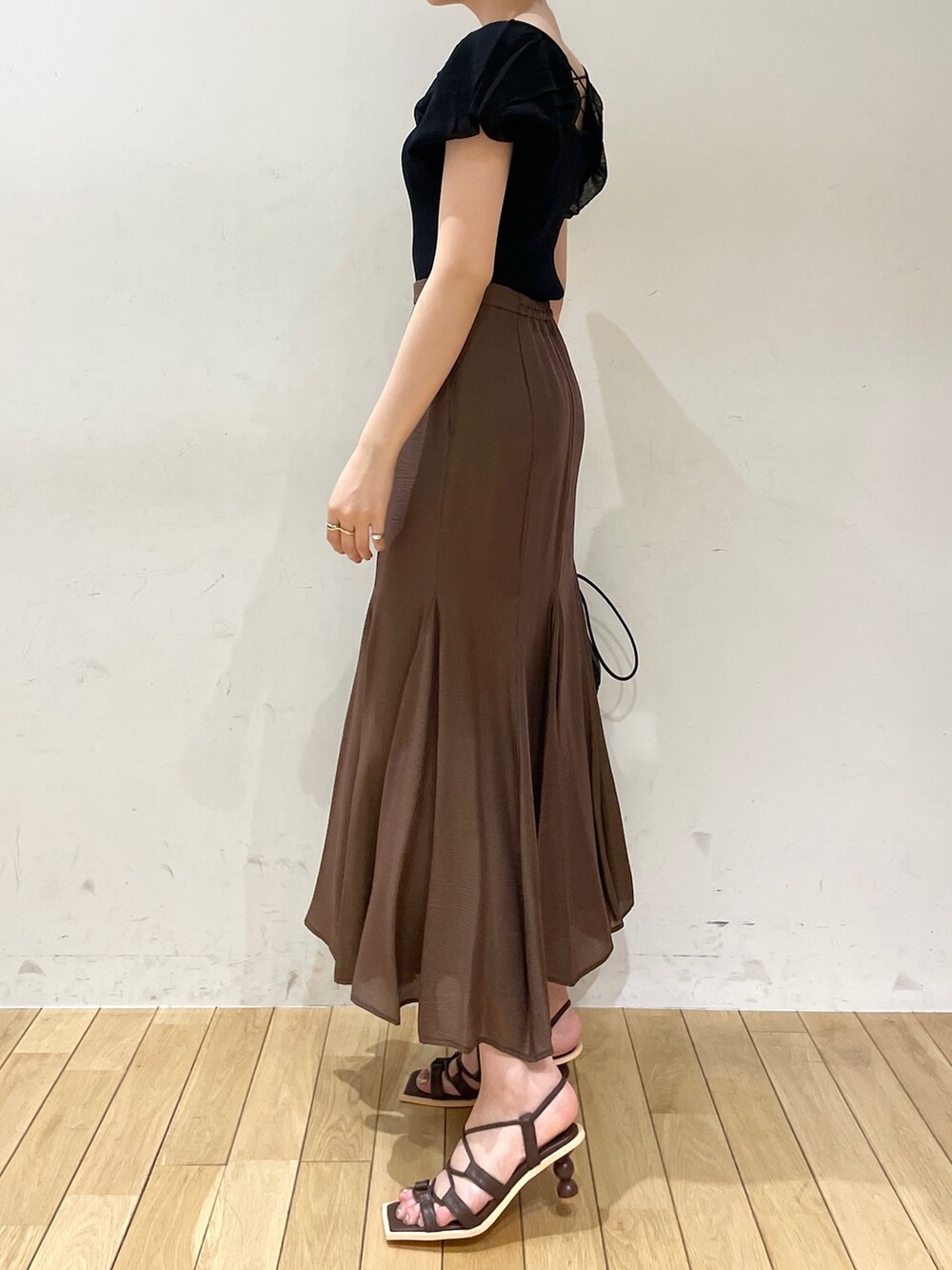 ブラウン系のスカート、ブラウン系のサンダル、ブラック系のハンドバッグを着用したレディースの夏コーディネートの4枚目の写真
