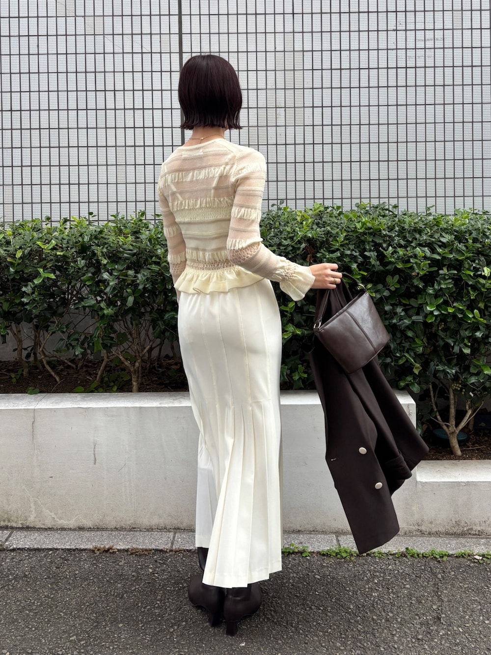 ホワイト系のニット/セーター、ホワイト系のスカート、ブラウン系のテーラードジャケットを着用したレディースの冬コーディネートの3枚目の写真