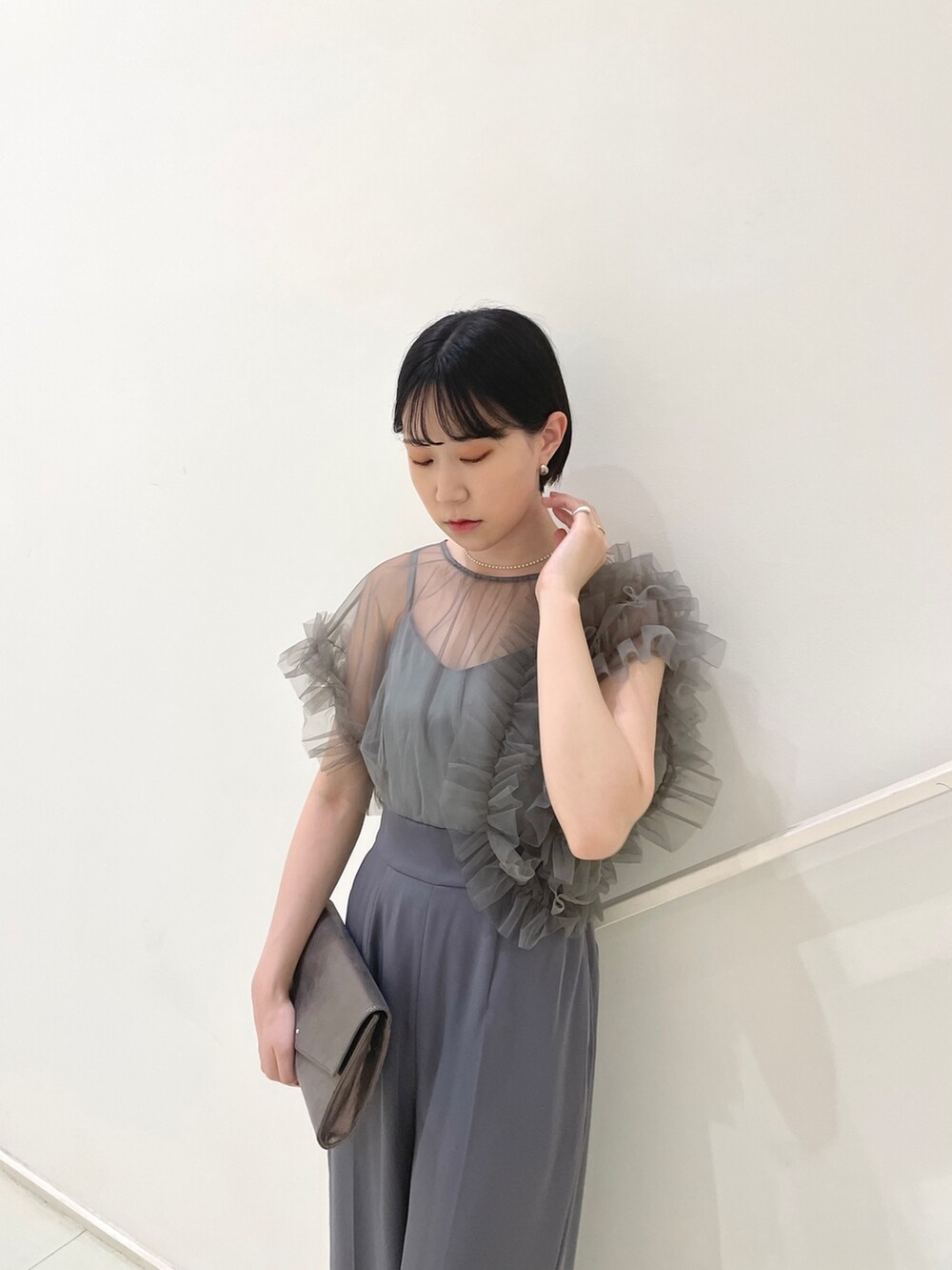 グレー系のパンツドレス、シルバー系のハンドバッグ、シルバー系のパンプスを着用したレディースの春コーディネートの6枚目の写真