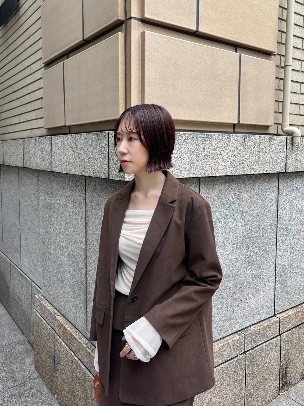 ブラウン系のブーツ、ブラウン系のハンドバッグ、ブラウン系のスカートを着用したレディースの秋コーディネートの2枚目の写真