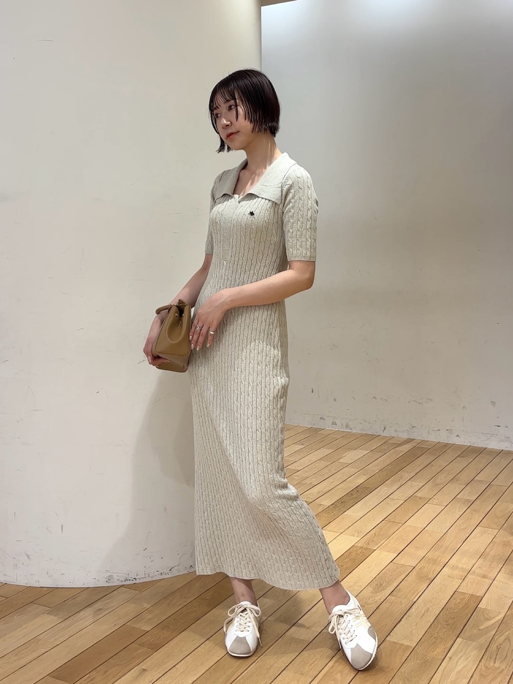 ベージュ系のワンピース、イエロー系のハンドバッグ、ベージュ系のスニーカーを着用したレディースの春コーディネートの3枚目の写真