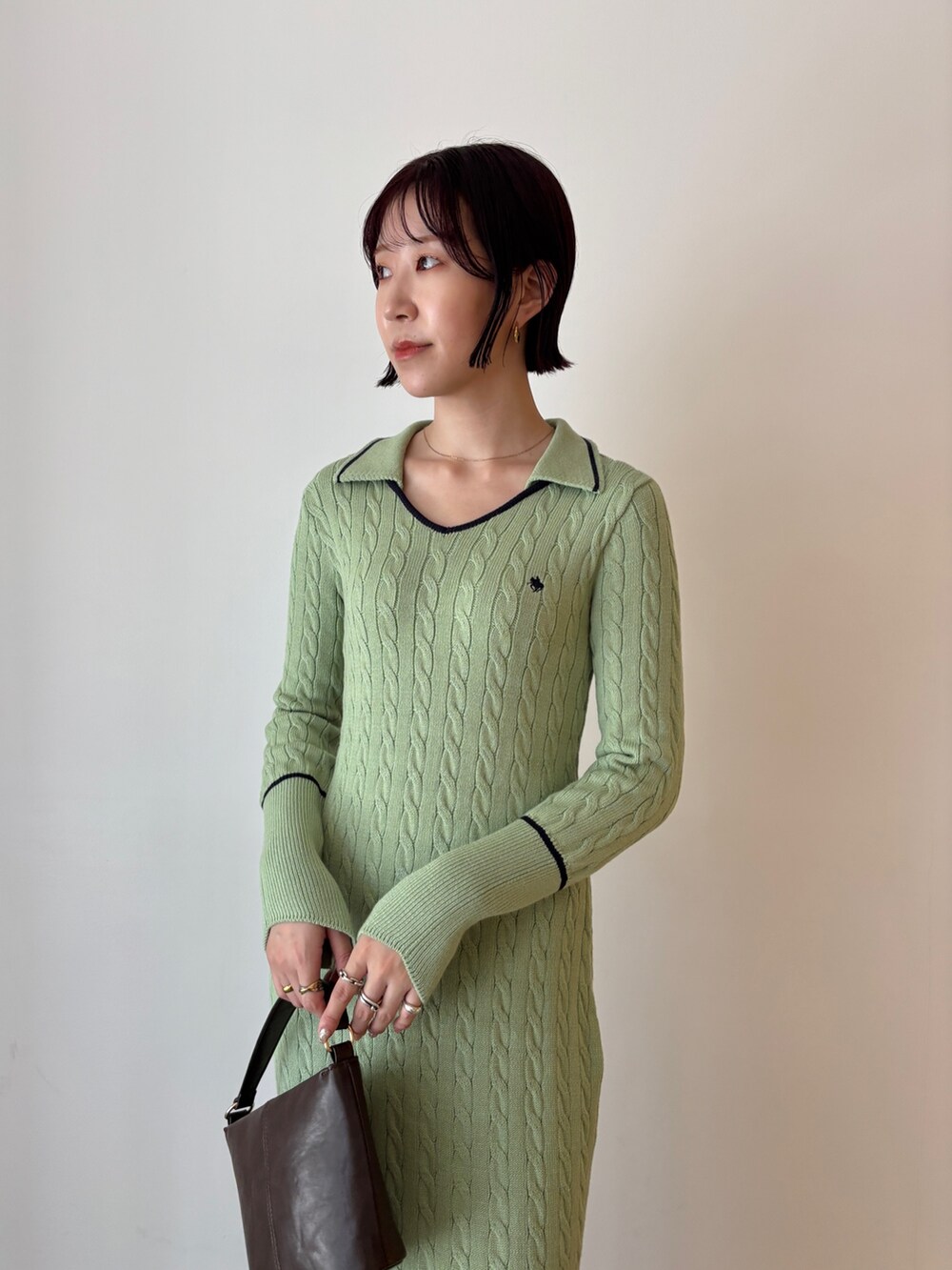 グリーン系のワンピース、ブラウン系のハンドバッグ、ブラウン系のブーツを着用したレディースの秋コーディネートの4枚目の写真