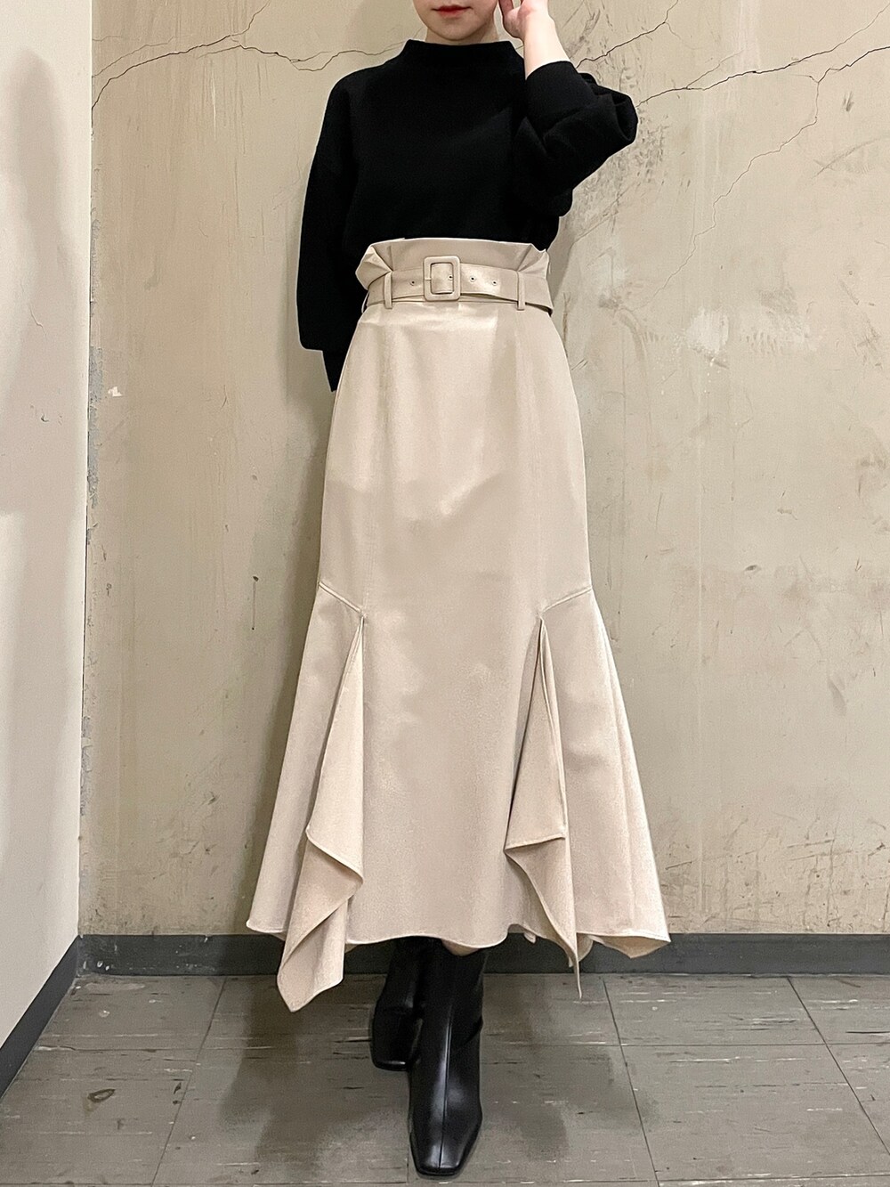 ベージュ系のスカート、ブラック系のニット/セーター、ブラック系のブーツを着用したレディースの秋コーディネートの2枚目の写真