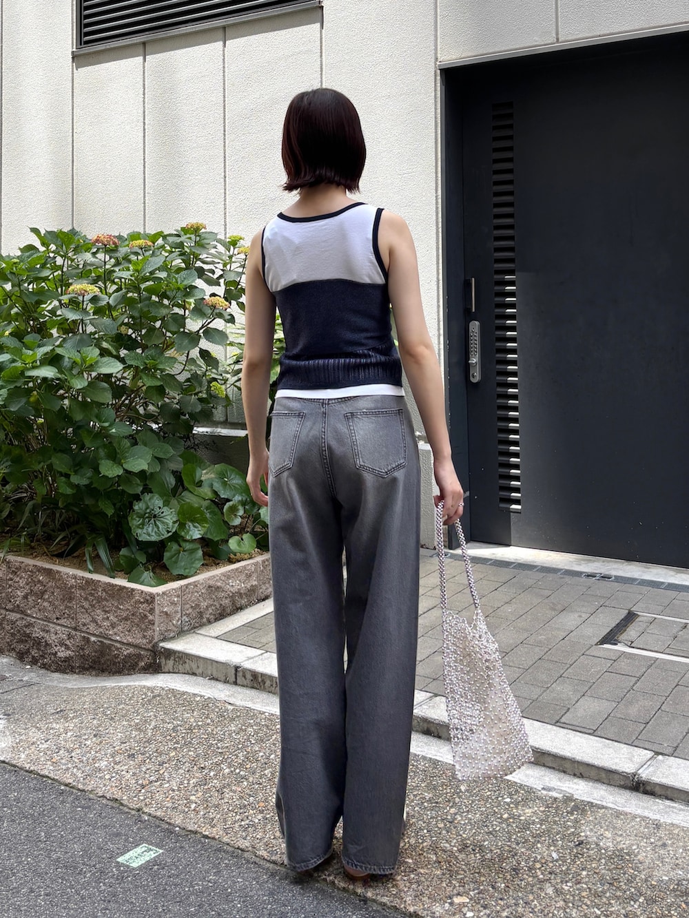 グレー系のデニムパンツ、ホワイト系のニット/セーター、ホワイト系のハンドバッグを着用したレディースの春コーディネートの3枚目の写真