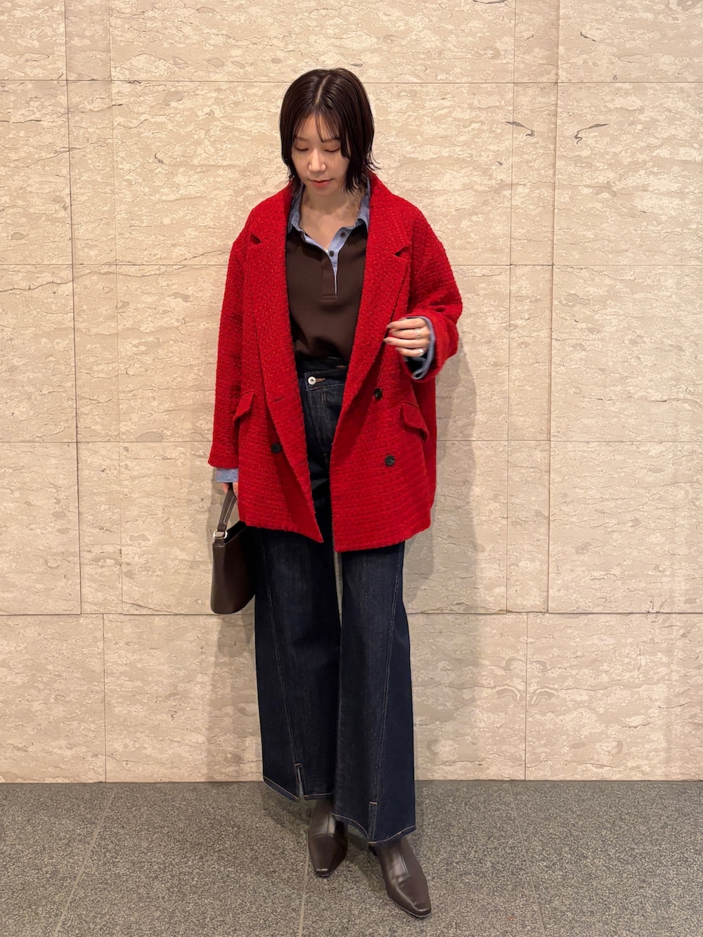 ブルー系のデニムパンツ、ブラウン系のニット/セーター、ブラウン系のハンドバッグを着用したレディースの冬コーディネートの2枚目の写真