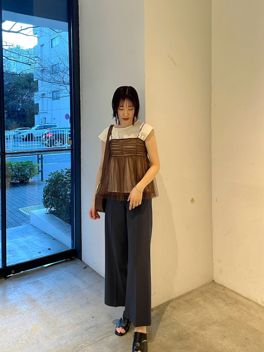 ブラウン系のTシャツ/カットソー、ブルー系のスラックス、ブラック系のサンダルを着用したレディースの春コーディネートの2枚目の写真