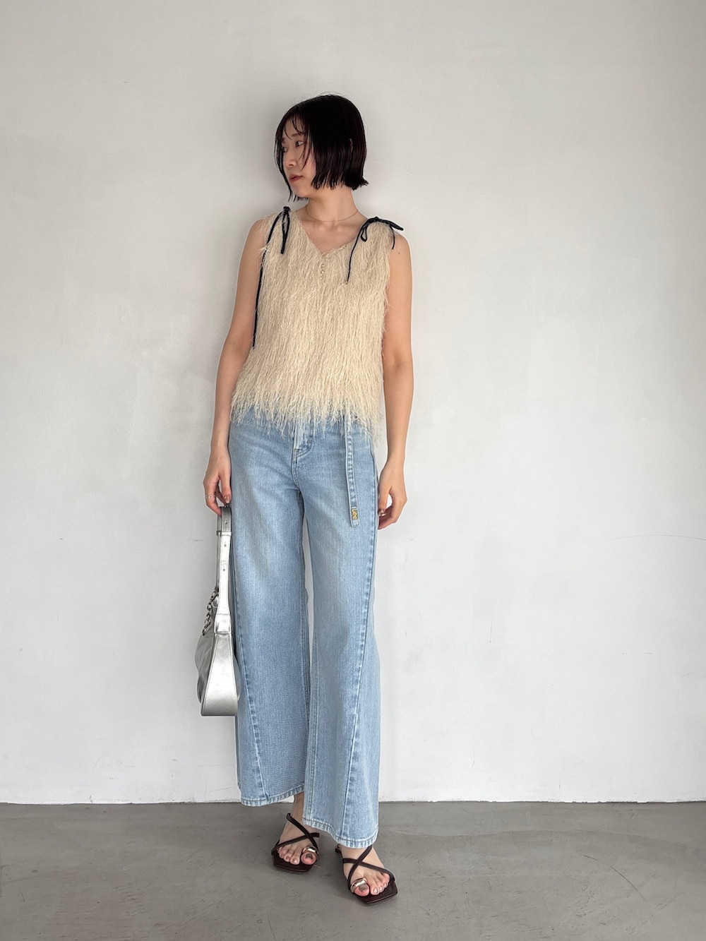 ホワイト系のTシャツ/カットソー、ブルー系のデニムパンツ、シルバー系のハンドバッグを着用したレディースの春コーディネートの2枚目の写真