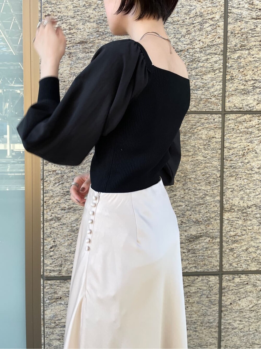 ホワイト系のスカート、ホワイト系のノーカラーコート、ブラック系のニット/セーターを着用したレディースの冬コーディネートの6枚目の写真