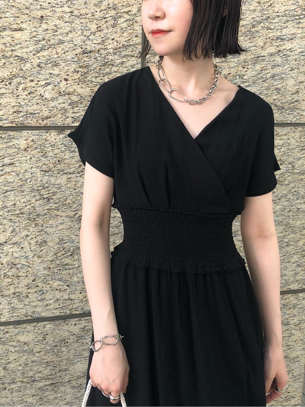 ブラック系のワンピース、ブラウン系のサンダル、シルバー系のブレスレットを着用したレディースの夏コーディネートの5枚目の写真