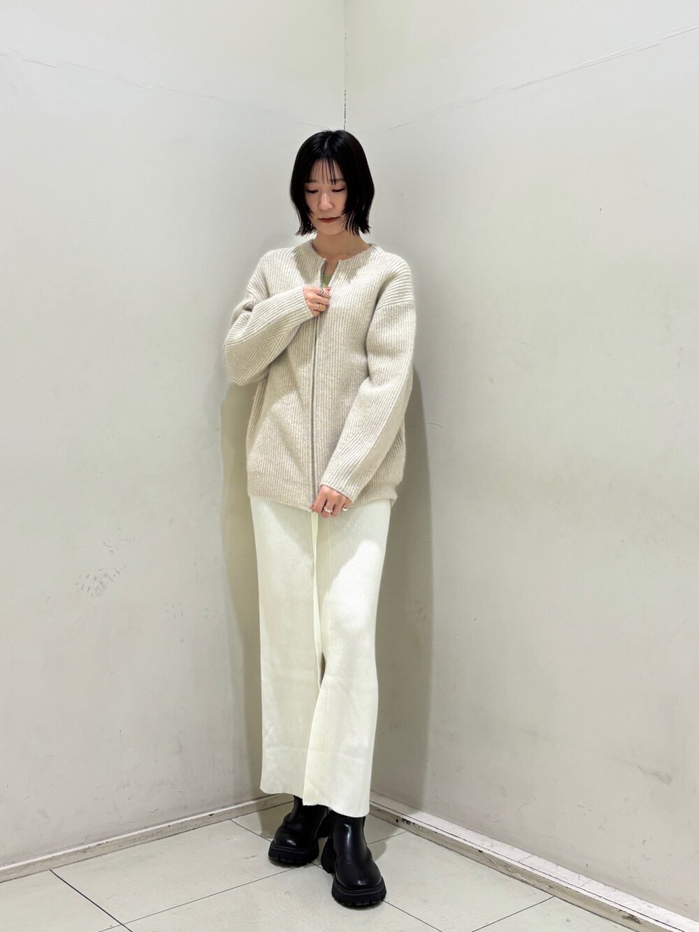 グリーン系のニット/セーター、ホワイト系のワンピース、ホワイト系のカーディガン/ボレロを着用したレディースの冬コーディネートの4枚目の写真