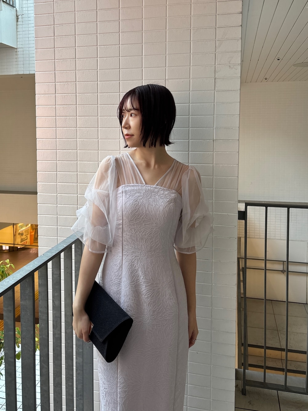 パープル系のドレス、ブラック系のハンドバッグ、ブラック系のパンプスを着用したレディースの冬コーディネートの4枚目の写真