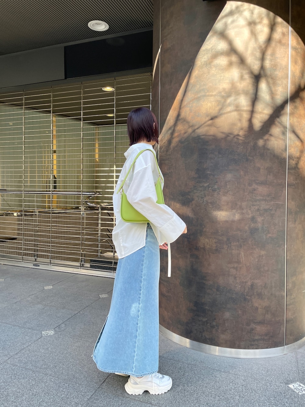 ホワイト系のシャツ/ブラウス、グリーン系のデニムスカート、ホワイト系のスニーカーを着用したレディースの春コーディネートの4枚目の写真