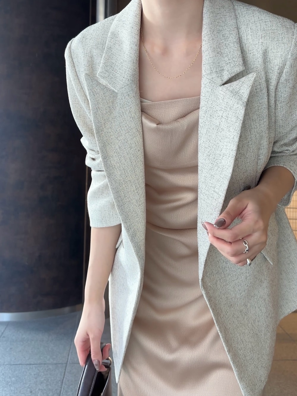 ホワイト系のテーラードジャケット、ブラウン系のハンドバッグ、ブラウン系のブーツを着用したレディースの冬コーディネートの5枚目の写真