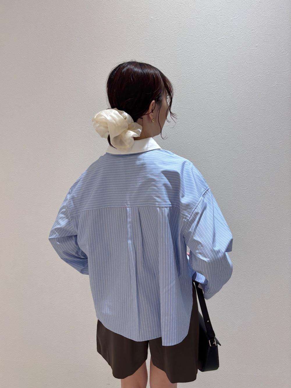 ブルー系のシャツ/ブラウス、ブラック系のハンドバッグ、ブラック系のブーツを着用したレディースの夏コーディネートの7枚目の写真