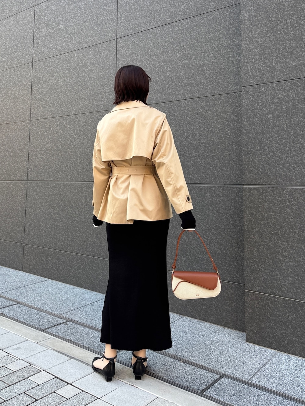 ブラック系のワンピース、ブラウン系のハンドバッグ、ブラック系のパンプスを着用したレディースの春コーディネートの6枚目の写真