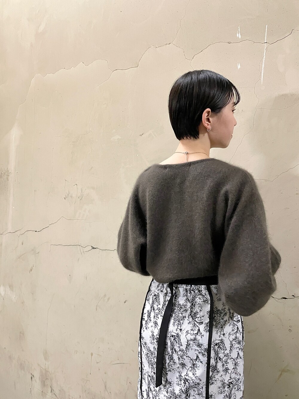 ブラック系のブーツ、ブラウン系のニット/セーター、ブラック系のスカートを着用したレディースの秋コーディネートの6枚目の写真