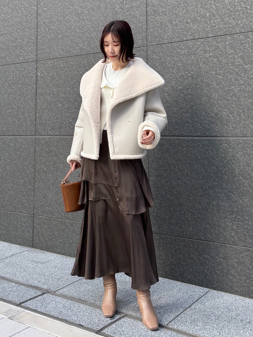 ブラウン系のスカート、イエロー系のハンドバッグ、ベージュ系のブーツを着用したレディースの冬コーディネートの5枚目の写真