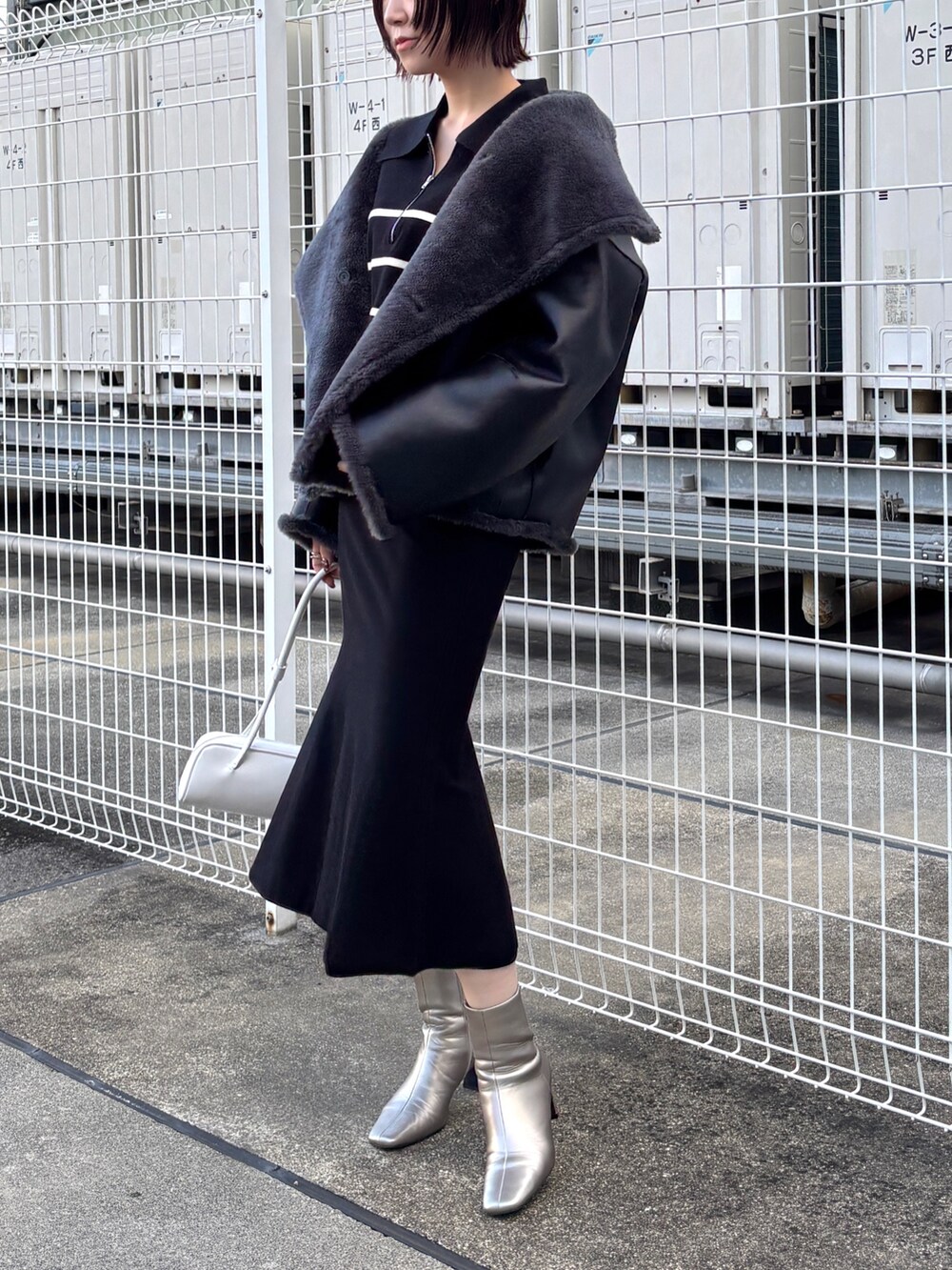ブラック系のニット/セーター、ブラック系のスカート、グレー系のムートンコートを着用したレディースの冬コーディネートの5枚目の写真