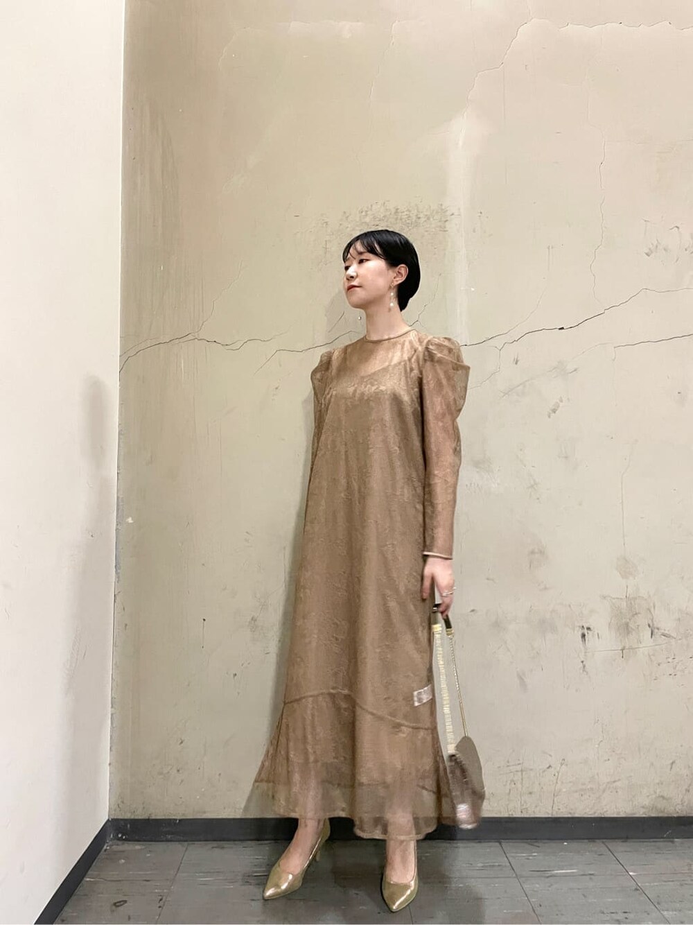 ゴールド系のパンプス、ベージュ系のドレス、ゴールド系のハンドバッグを着用したレディースの秋コーディネートの3枚目の写真