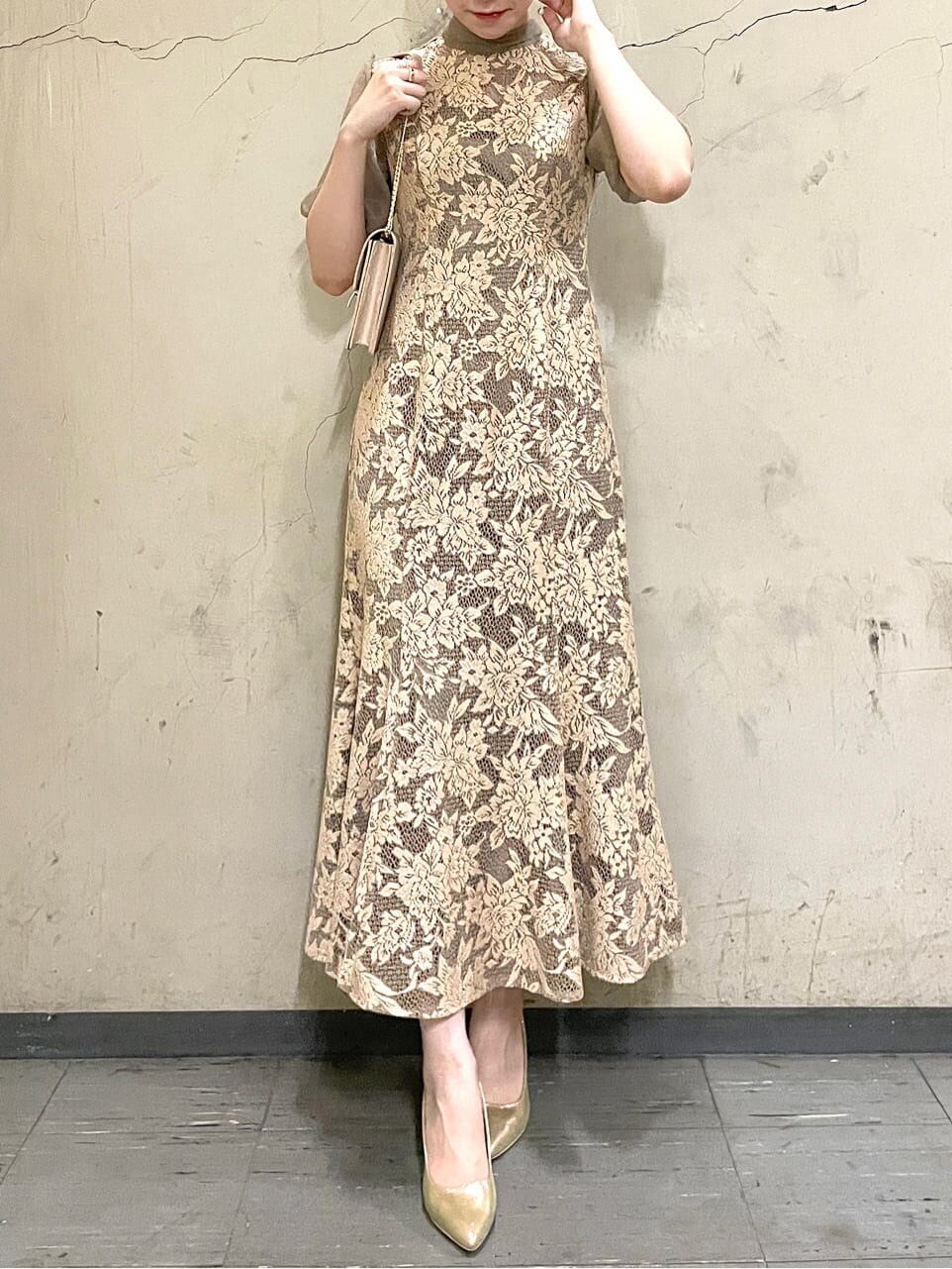 ベージュ系のドレス、ゴールド系のパンプス、ベージュ系のクラッチバッグを着用したレディースの秋コーディネートの4枚目の写真