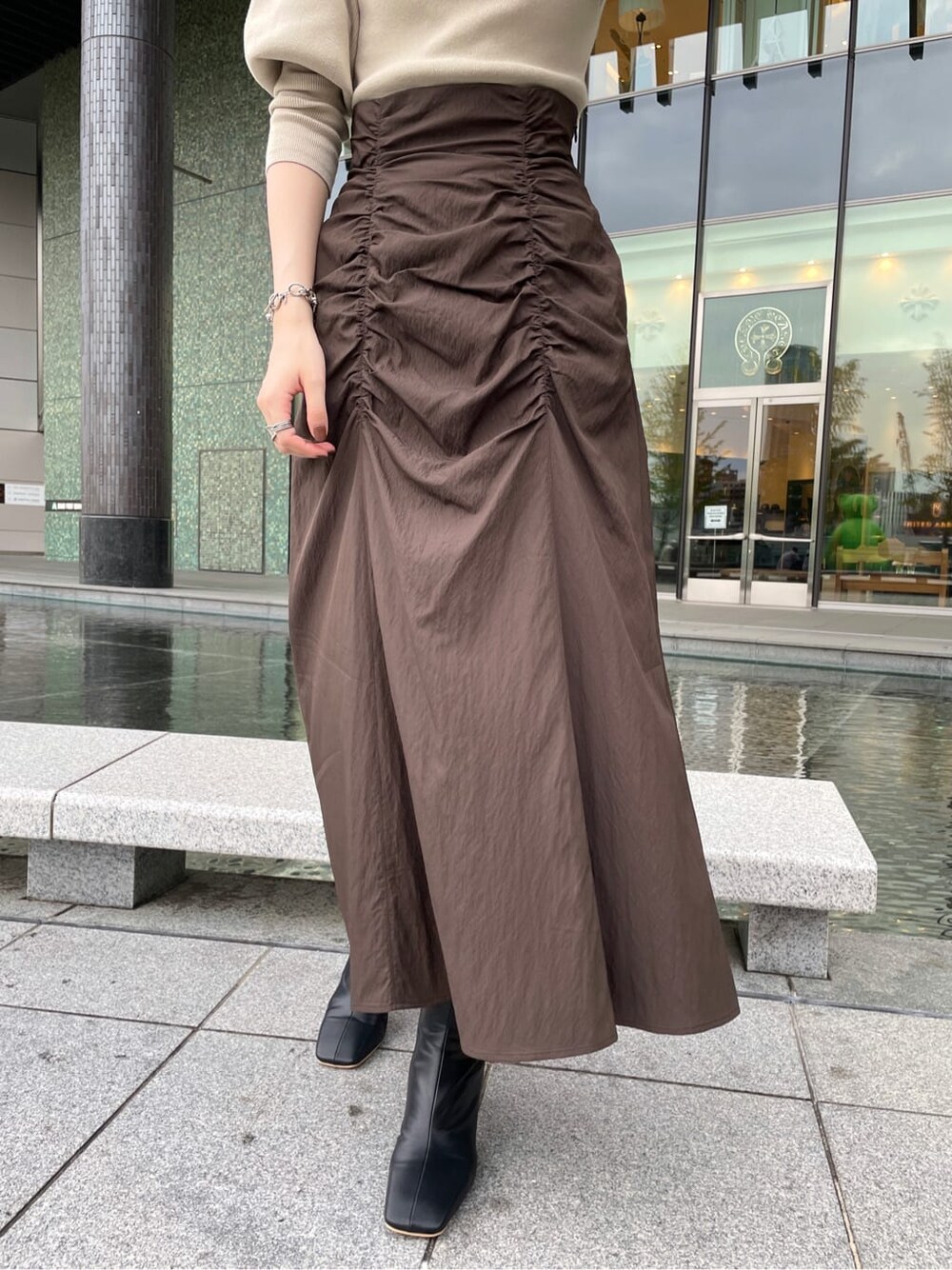 ブラック系のその他シューズ、ベージュ系のその他アウター、ブラウン系のスカートを着用したレディースの秋コーディネートの4枚目の写真