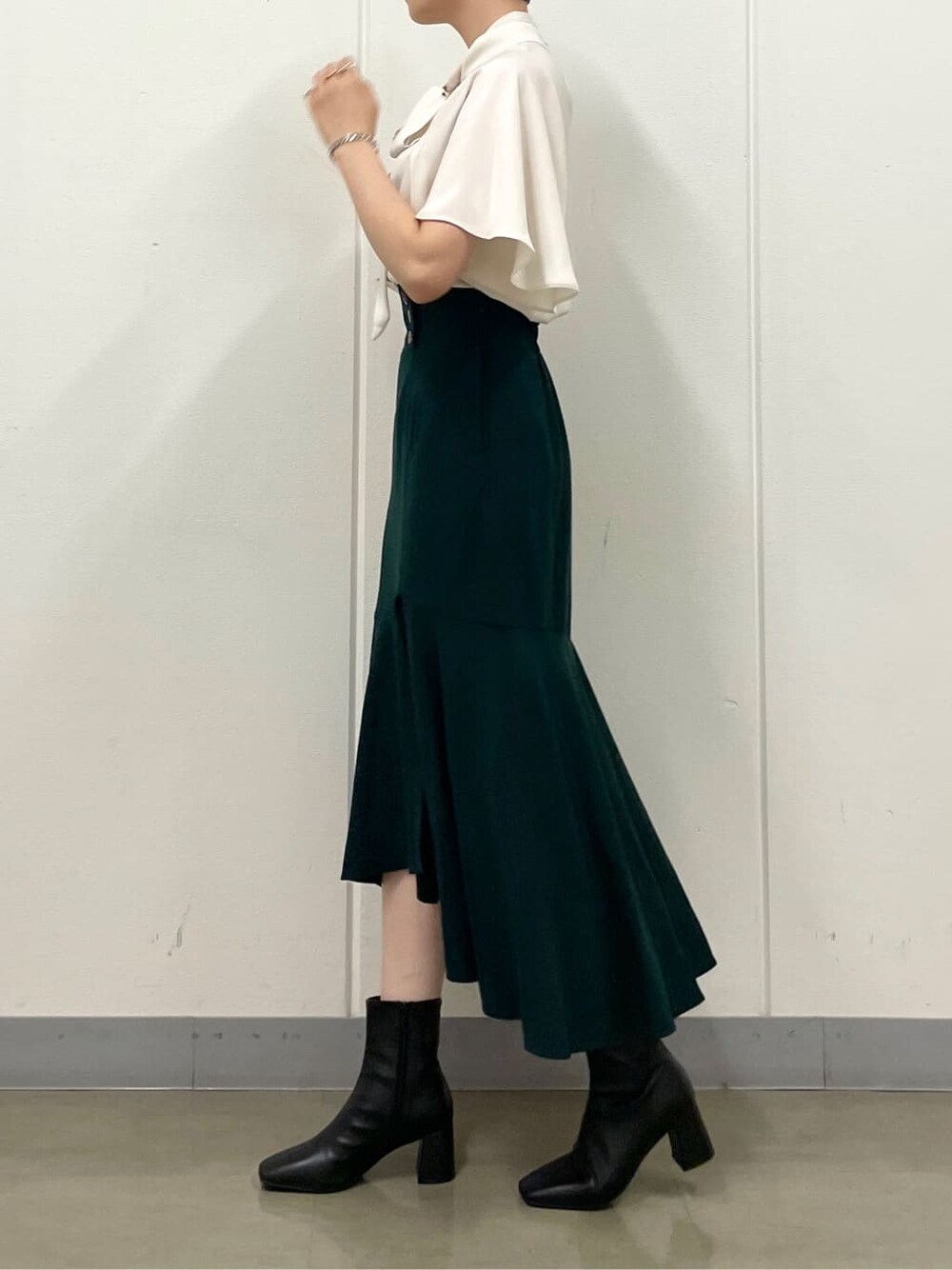 ホワイト系のシャツ/ブラウス、グリーン系のスカート、ブラック系のブーツを着用したレディースの秋コーディネートの5枚目の写真