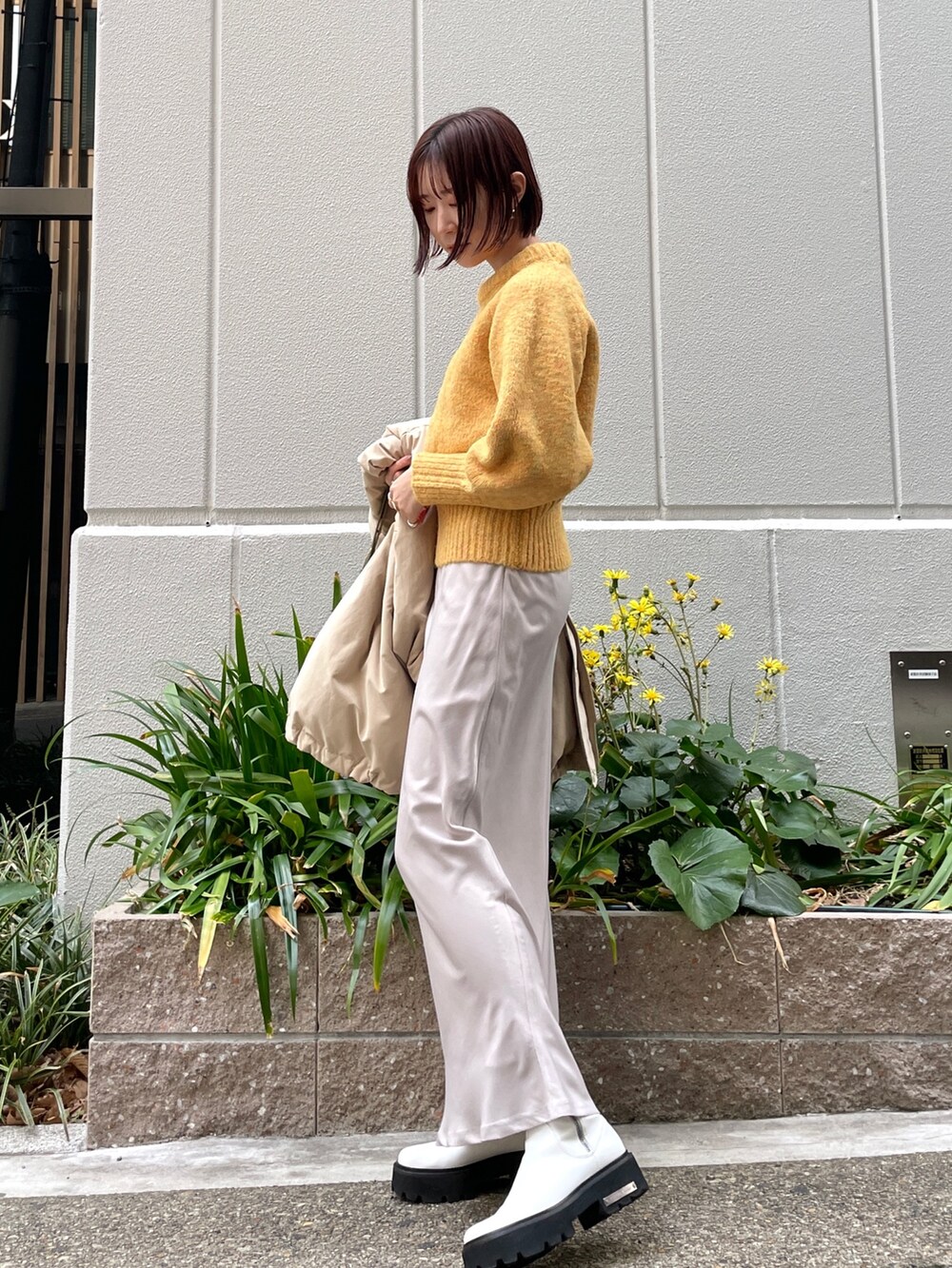 ベージュ系のダウンジャケット/コート、ホワイト系のスカート、ブラウン系のショルダーバッグを着用したレディースの冬コーディネートの7枚目の写真