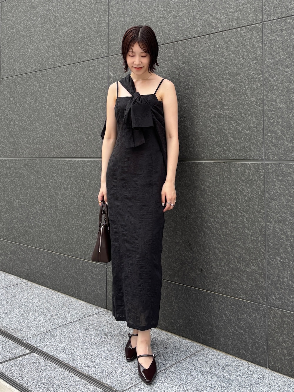 ブラック系のワンピース、ブラウン系のパンプス、ブラウン系のボストンバッグを着用したレディースの夏コーディネートの6枚目の写真