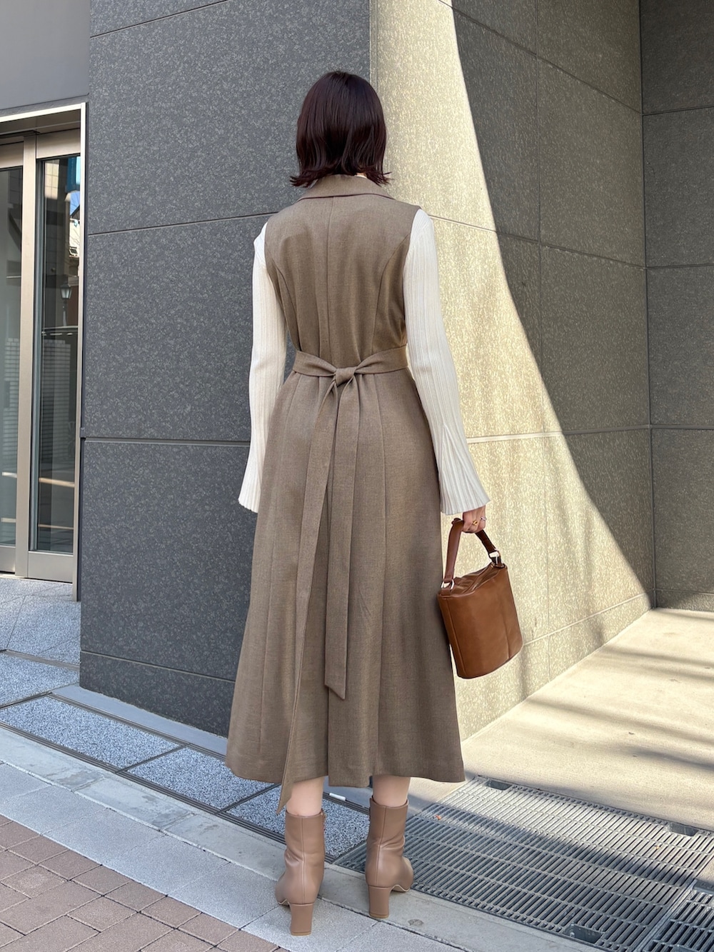 ブラウン系のワンピース、ホワイト系のニット/セーター、イエロー系のハンドバッグを着用したレディースの冬コーディネートの3枚目の写真