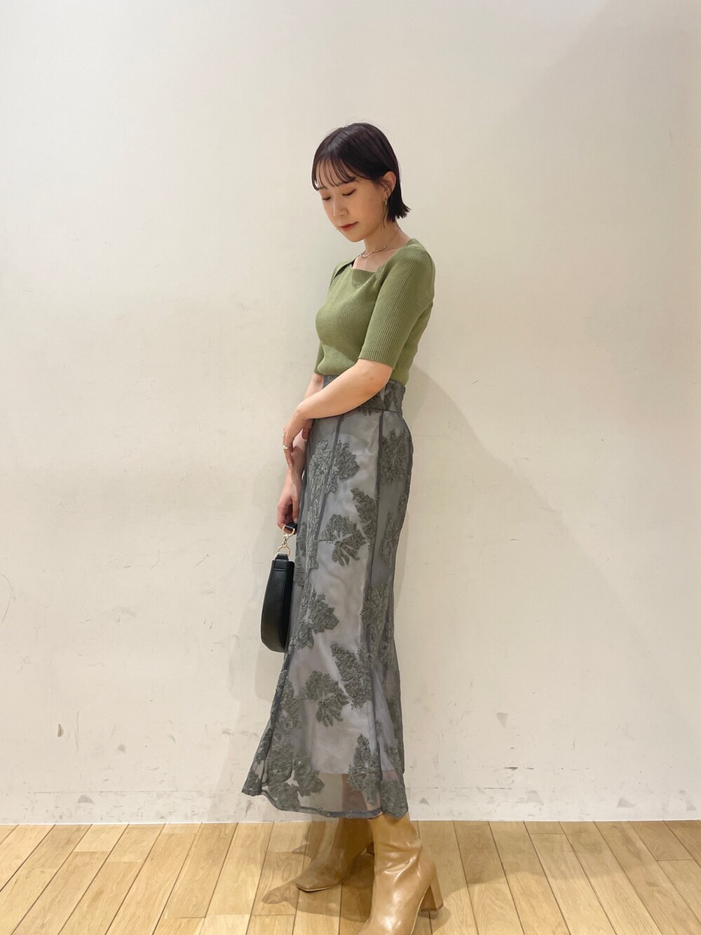 ベージュ系のブーツ、グリーン系のニット/セーター、グレー系のスカートを着用したレディースの夏コーディネートの4枚目の写真