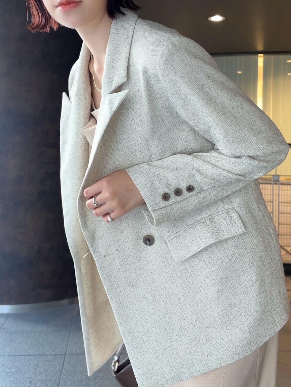 ホワイト系のテーラードジャケット、ブラウン系のハンドバッグ、ブラウン系のブーツを着用したレディースの冬コーディネートの6枚目の写真