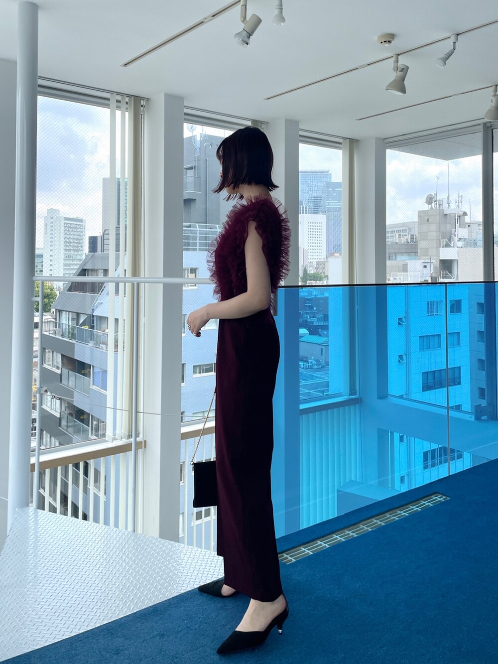 レッド系のパンツドレスを着用したレディースの春コーディネートの3枚目の写真