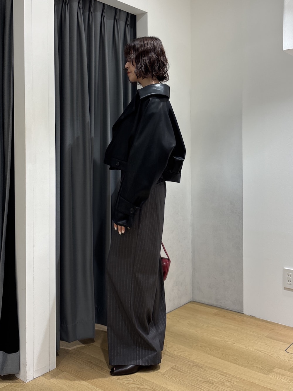 グレー系のその他パンツ、ホワイト系のニット/セーター、レッド系のハンドバッグを着用したレディースの秋コーディネートの3枚目の写真