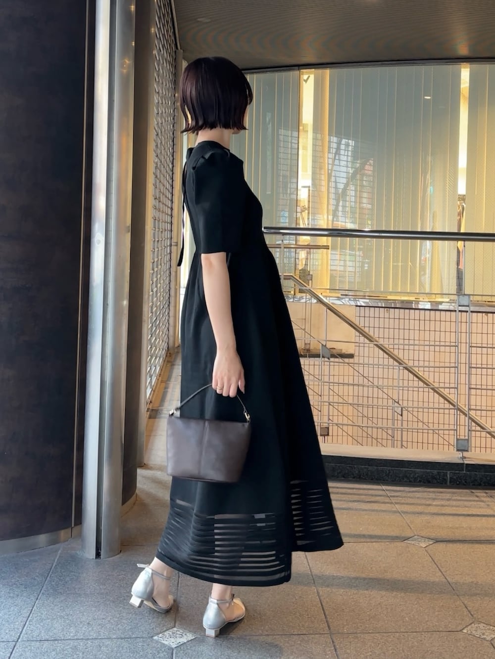 ブラウン系のハンドバッグ、シルバー系のパンプス、ブラック系のワンピースを着用したレディースの冬コーディネートの4枚目の写真