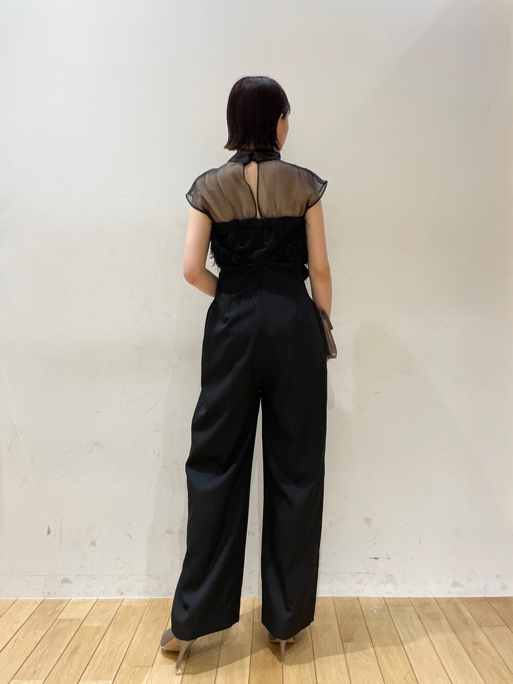 シルバー系のハンドバッグ、ブラック系のパンツドレス、シルバー系のパンプスを着用したレディースの秋コーディネートの4枚目の写真