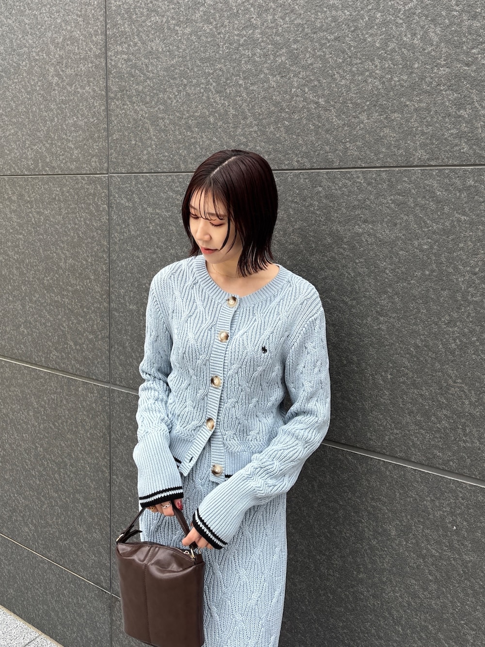 ブルー系のワンピース、ブラウン系のハンドバッグ、ブラウン系のパンプスを着用したレディースの冬コーディネートの6枚目の写真