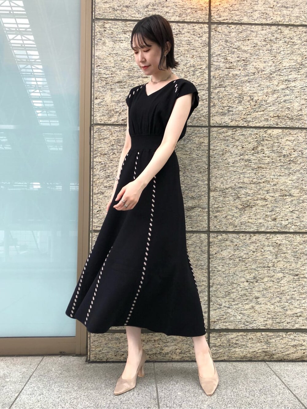 ブラック系のワンピース、ベージュ系のパンプス、ホワイト系のショルダーバッグを着用したレディースの夏コーディネートの2枚目の写真