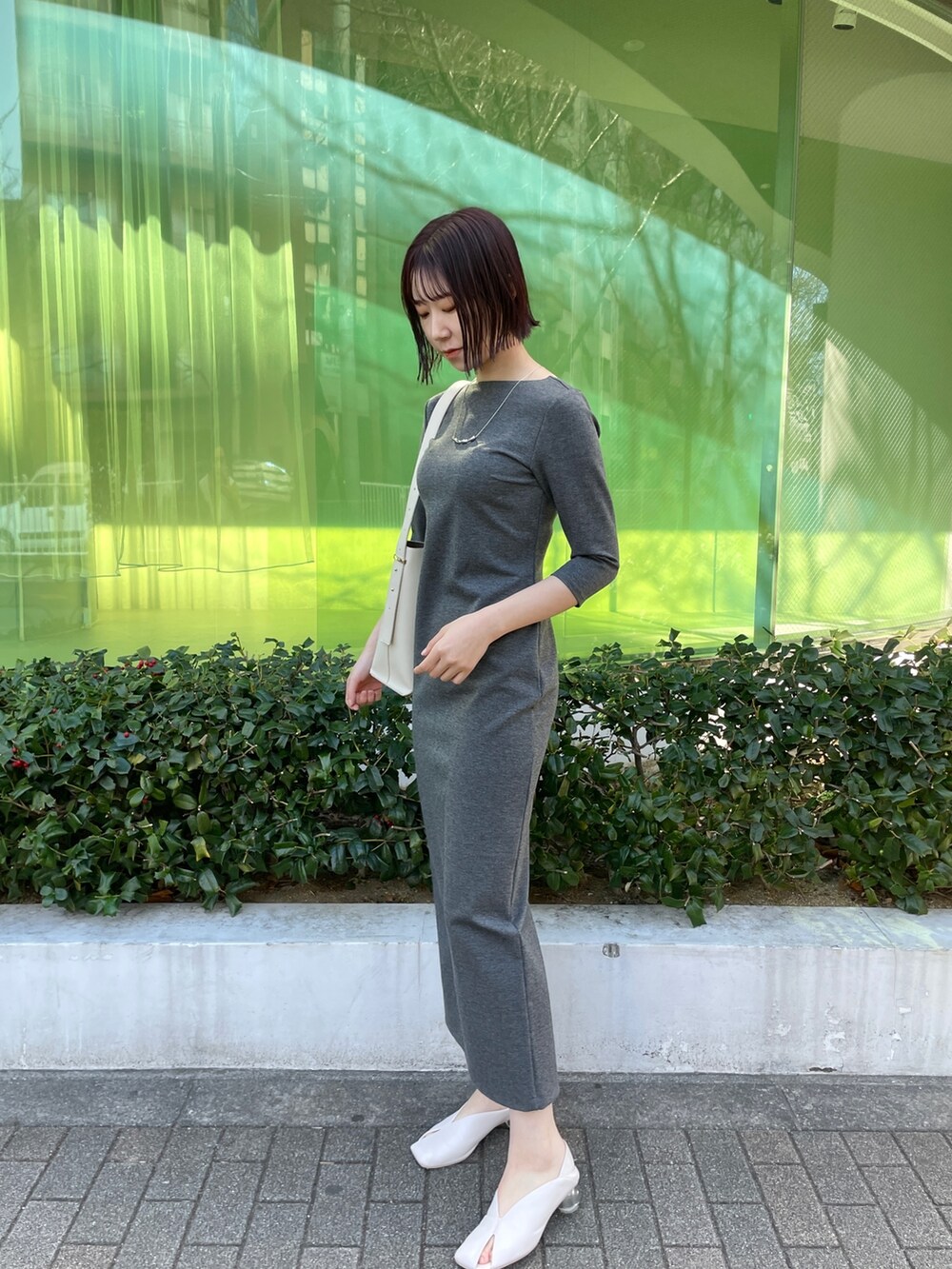 グレー系のワンピース、ホワイト系のショルダーバッグ、ホワイト系のパンプスを着用したレディースの冬コーディネートの2枚目の写真