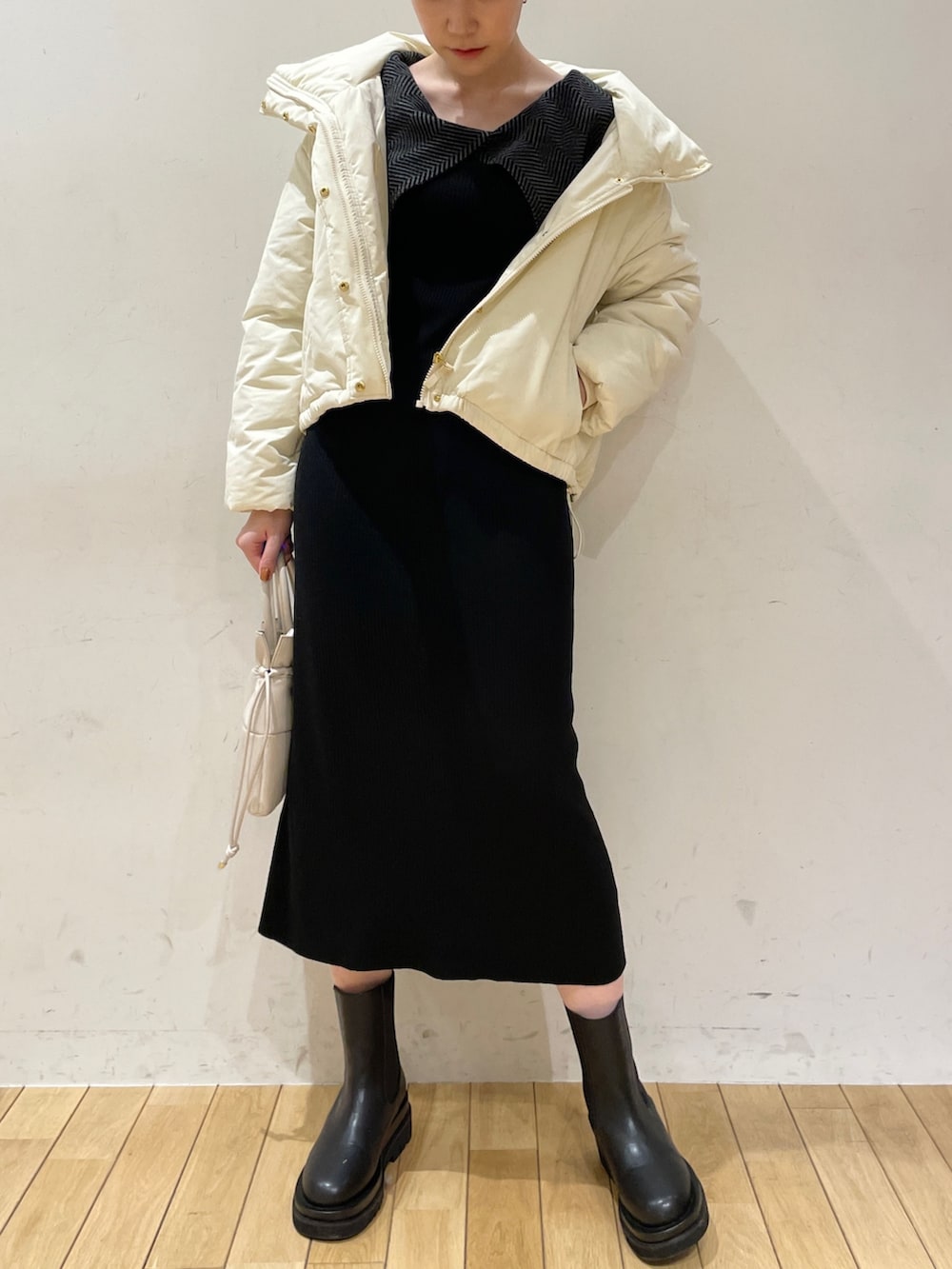 ホワイト系のダウンジャケット/コート、ブラック系のワンピース、ブラック系のブーツを着用したレディースの冬コーディネートの6枚目の写真