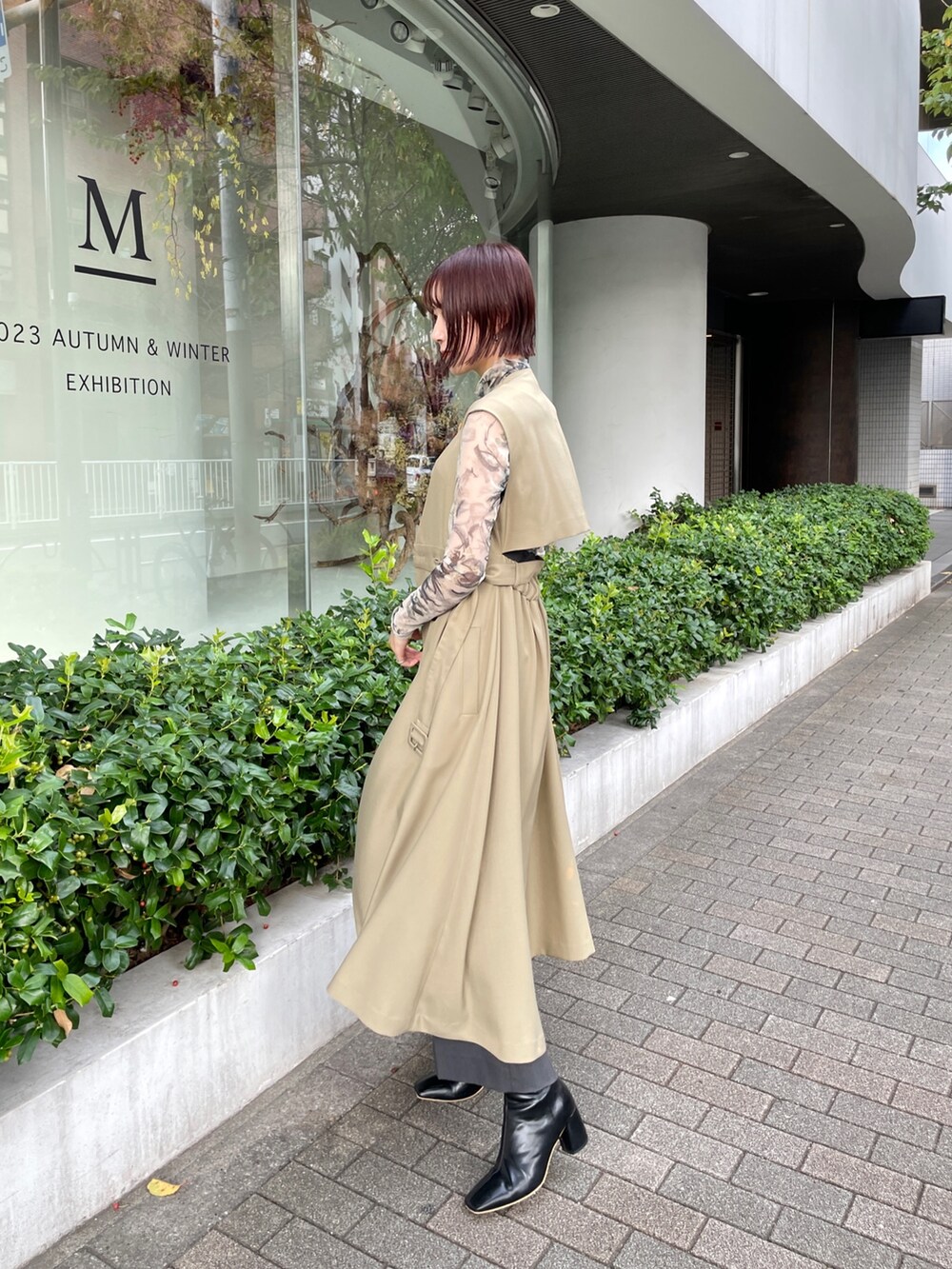 ブラック系のブーツ、グレー系のその他パンツ、グリーン系のトレンチコートを着用したレディースの冬コーディネートの3枚目の写真