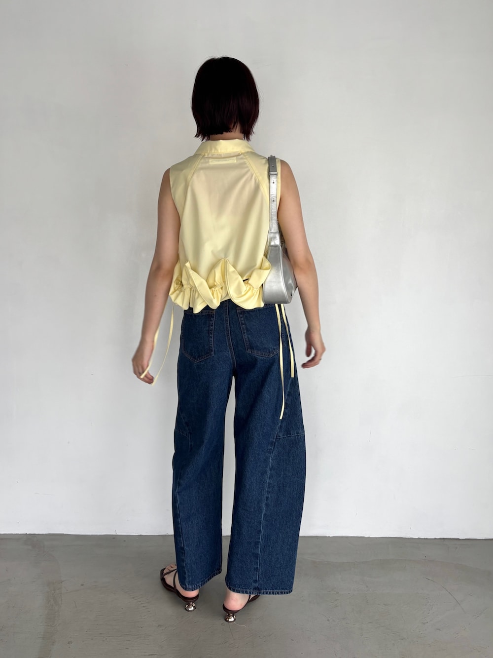 ブルー系のデニムパンツ、イエロー系のシャツ/ブラウス、シルバー系のハンドバッグを着用したレディースの夏コーディネートの3枚目の写真