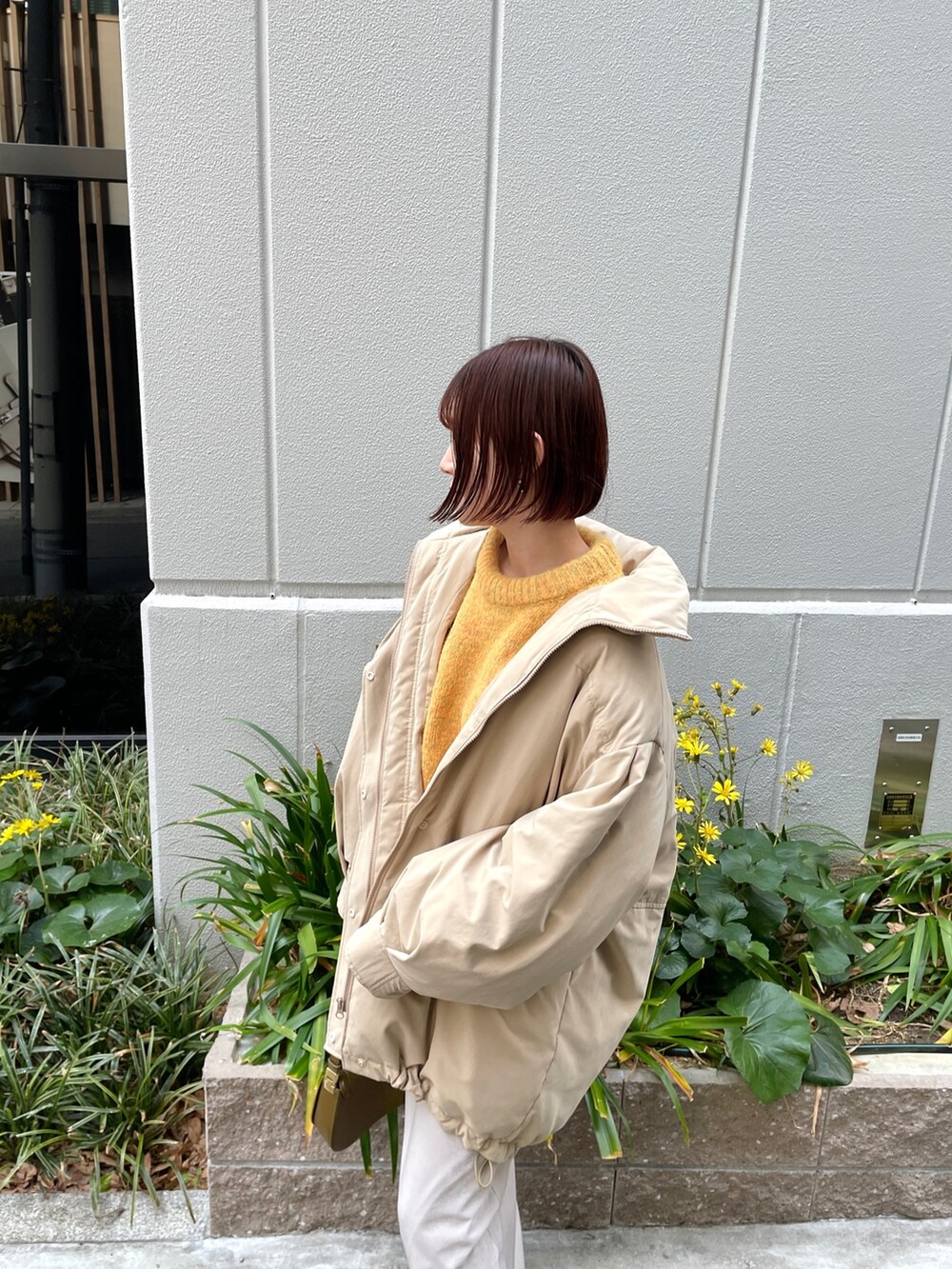 ベージュ系のダウンジャケット/コート、ホワイト系のスカート、ブラウン系のショルダーバッグを着用したレディースの冬コーディネートの4枚目の写真