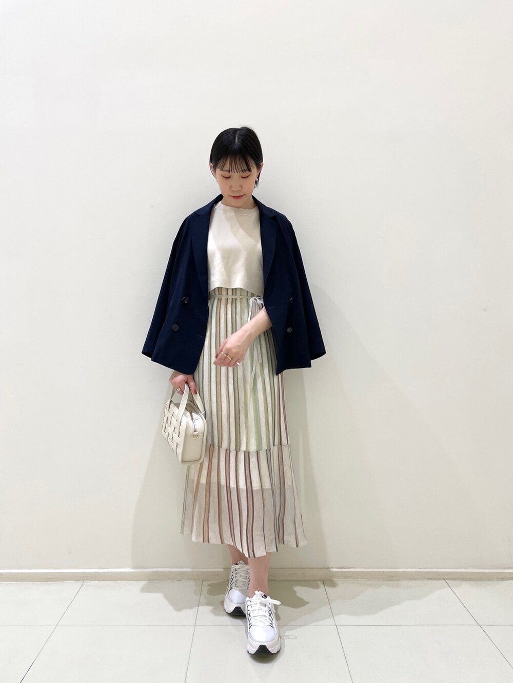 ブルー系のテーラードジャケット、ホワイト系のワンピース、ホワイト系のショルダーバッグを着用したレディースの春コーディネートの2枚目の写真