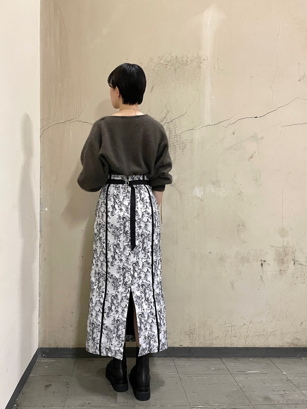 ブラック系のブーツ、ブラウン系のニット/セーター、ブラック系のスカートを着用したレディースの秋コーディネートの3枚目の写真