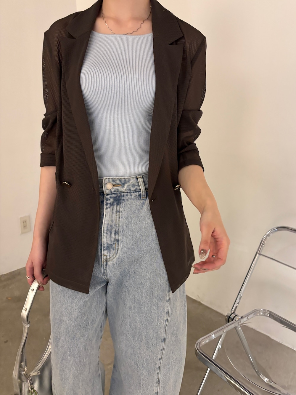 ブルー系のデニムパンツ、ブラウン系のテーラードジャケット、ブルー系のタンクトップを着用したレディースの春コーディネートの4枚目の写真