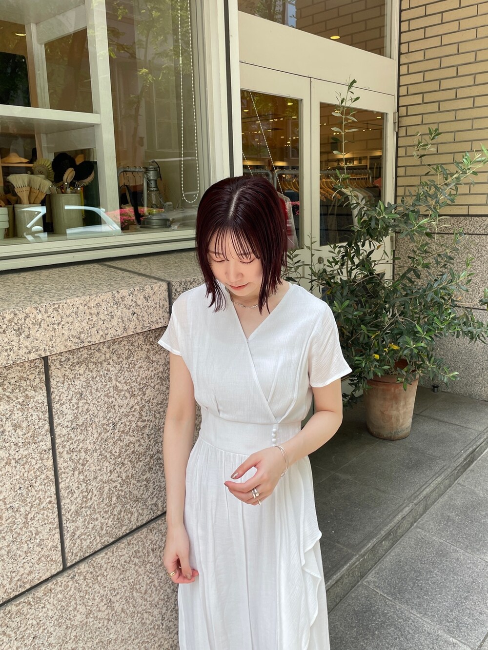 ブラウン系のショルダーバッグ、ホワイト系のワンピース、シルバー系のチョーカーを着用したレディースの夏コーディネートの5枚目の写真