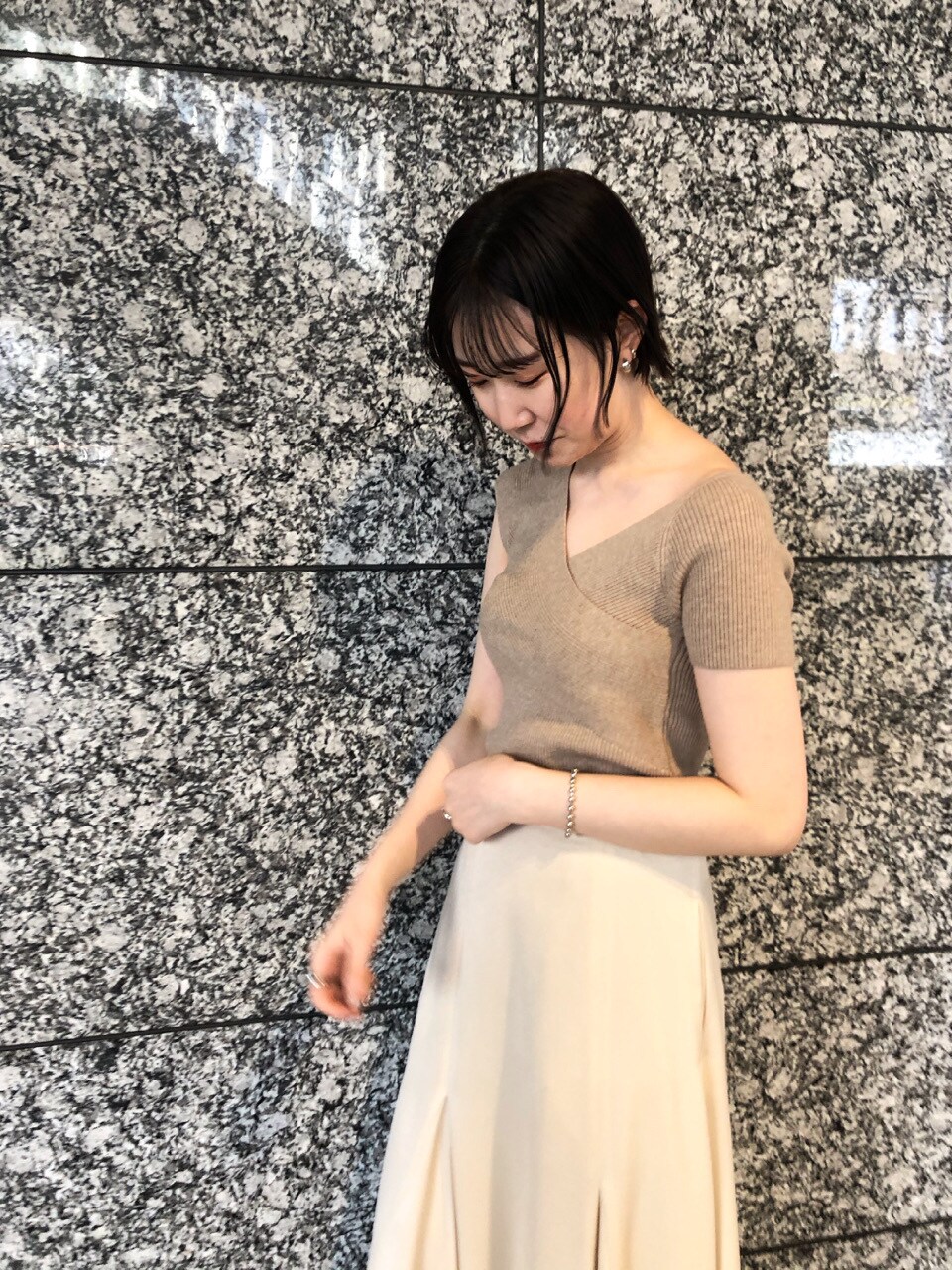 ベージュ系のニット/セーター、ホワイト系のスニーカー、ホワイト系のスカートを着用したレディースの春コーディネートの4枚目の写真