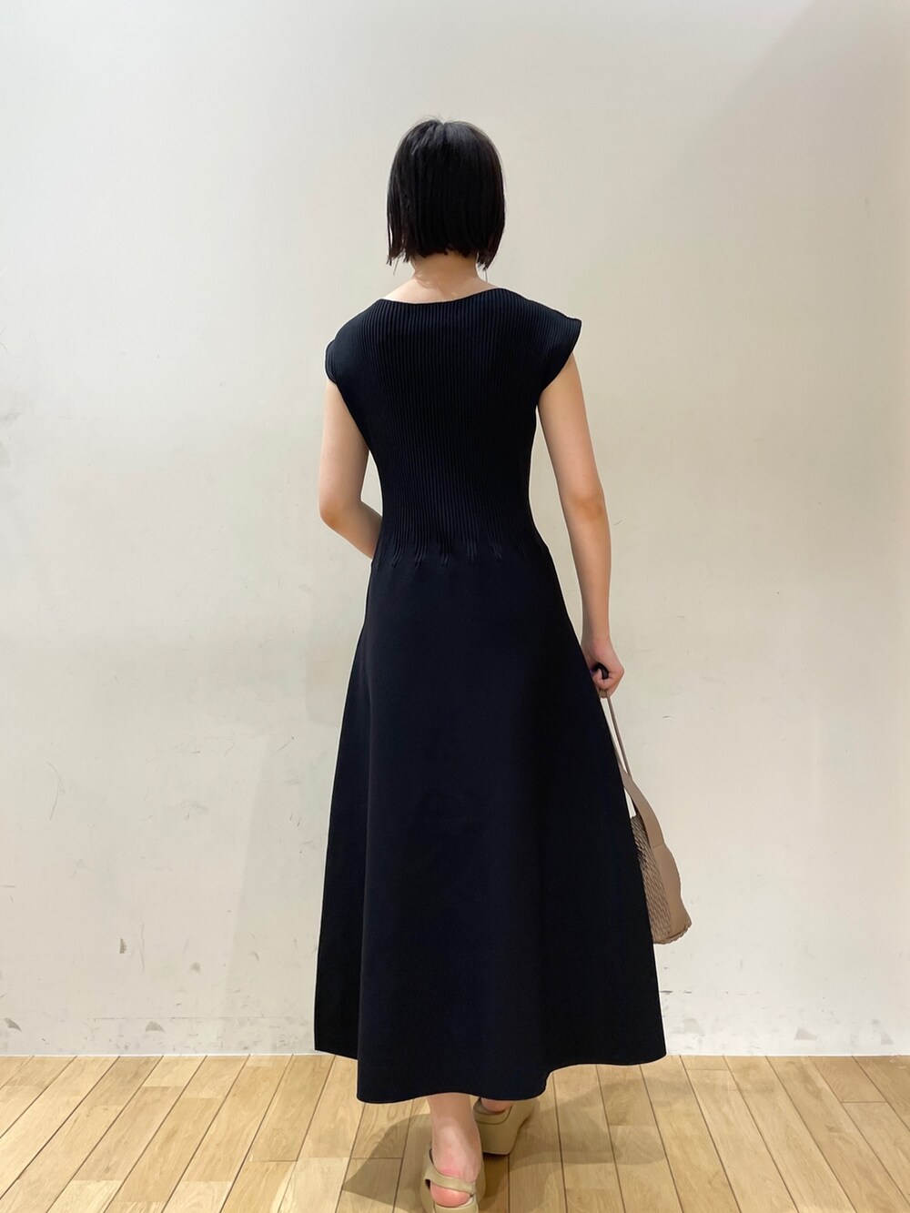 ブラック系のワンピース、ブラウン系のハンドバッグ、ベージュ系のサンダルを着用したレディースの夏コーディネートの5枚目の写真